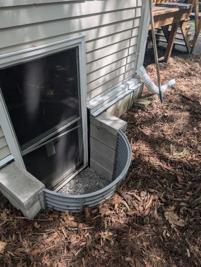 Completed window well repair with fresh gravel and repaired surround — after