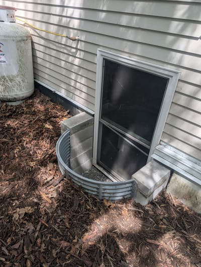 Repaired basement egress window well with new gravel drainage — after