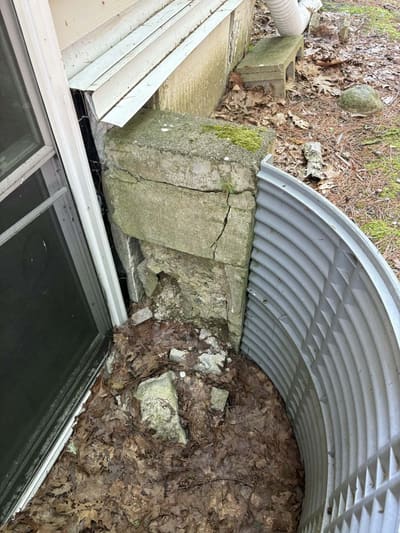 Damaged stone foundation and window well before repair
